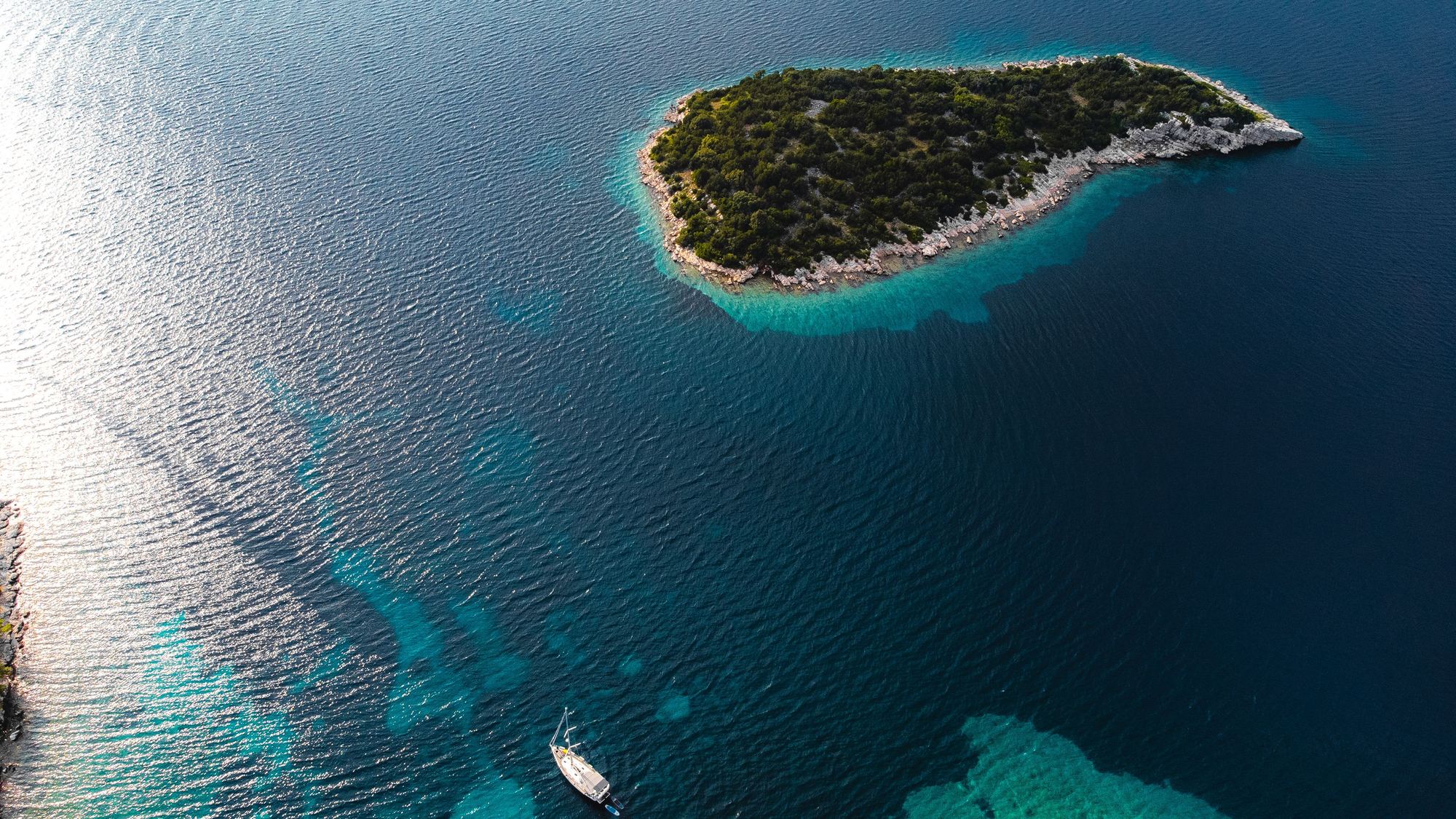 Pogled iz zraka na hrvatski otok i jedrilicu